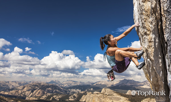 Woman rock climber scaling vertical wall.