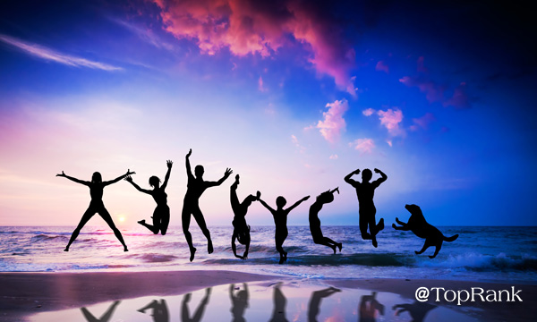 Happy people and dog jumping together on the sunset beach Image